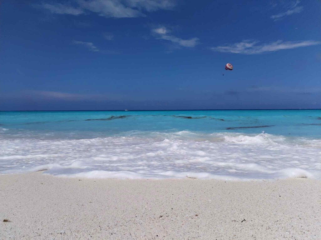 Playa azul turquesa con parachute al fondo